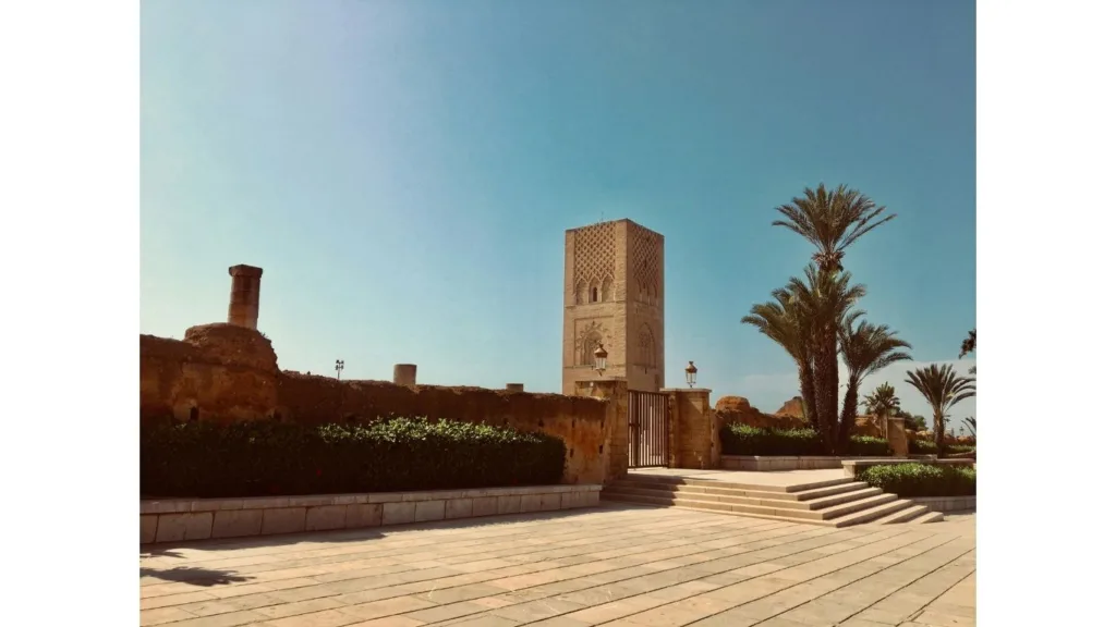 لقطة عمودية لصومعة حسان التاريخية في مدينة الرباط بالمغرب، تظهر البناء الحجري العريق مع أشجار النخيل تحت سماء صافية، وهي موقع مصنف ضمن التراث العالمي لليونسكو.